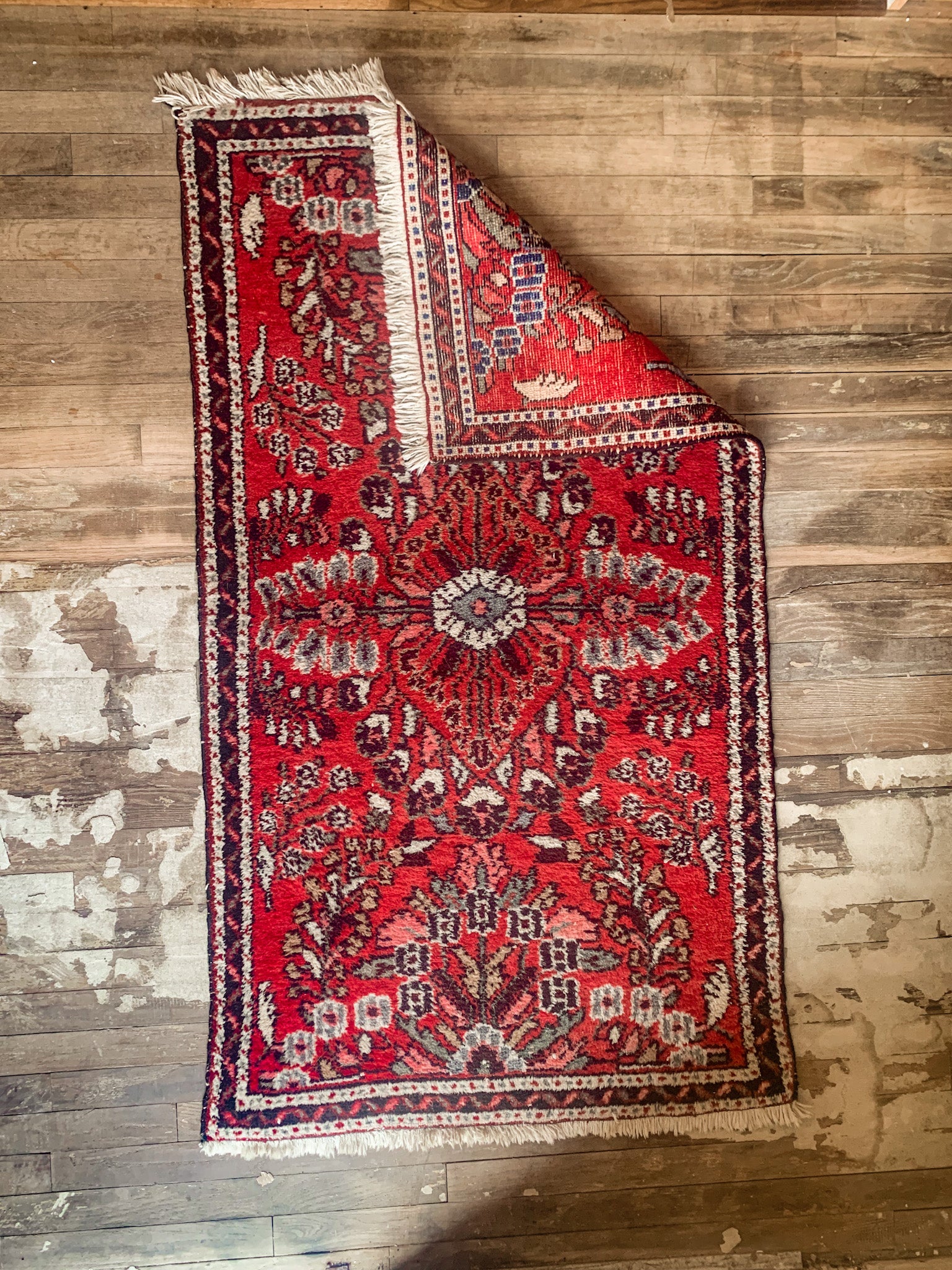 iranian lilihan rug with corner folded over to reveal weave pattern underneath