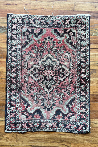 Woven vintage Persian mini rug in red, brown, and cream.