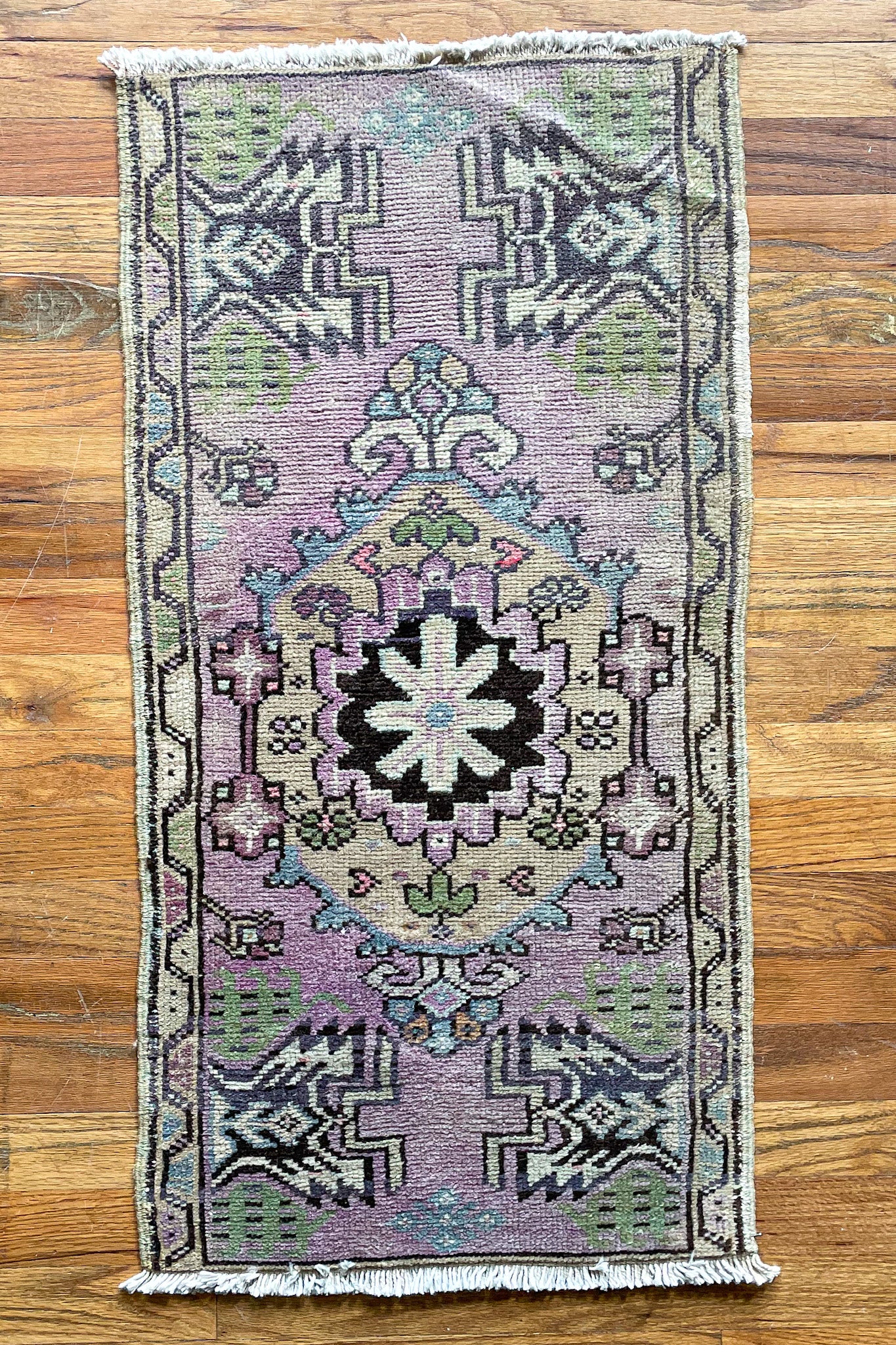 Woven vintage Turkish mini rug in purple, green, and black.