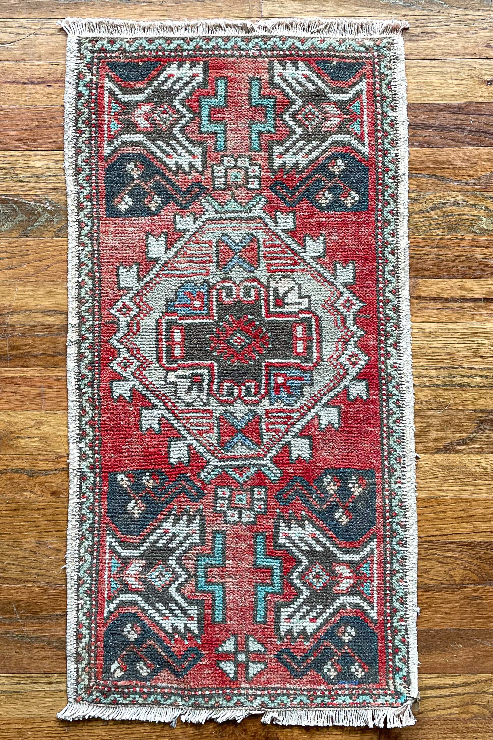 Woven vintage Turkish mini rug in red, brown, and cream.